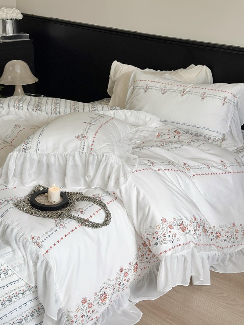 Lightly washed cotton bedding set with ruffled border and fine floral embroidery