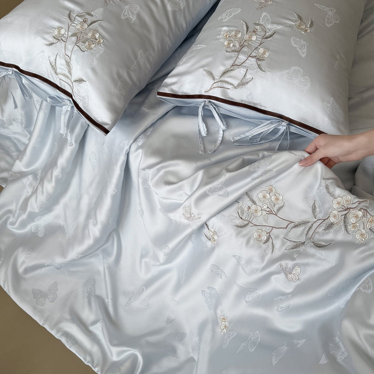 Light jacquard satin bed linen set with embroidered butterfly motif and decorative roll Bowlift